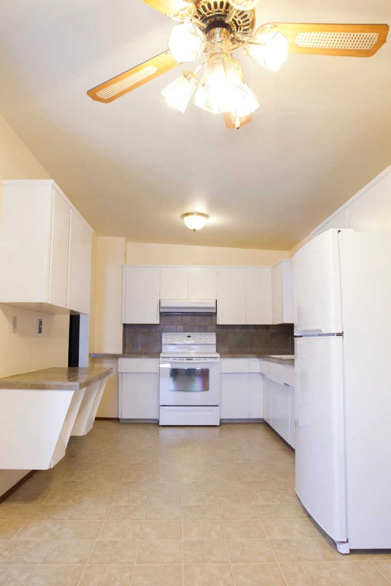 Bright kitchen with tiled floor and fridge.