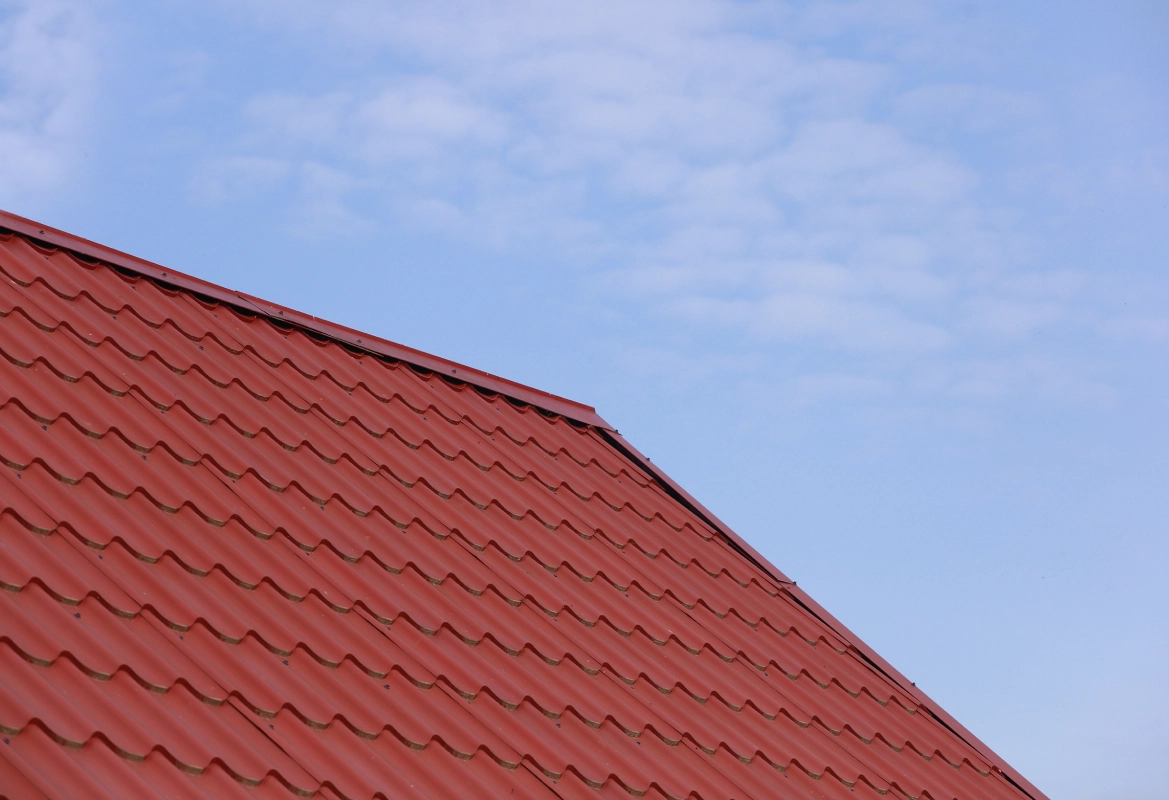 Corrugated red roof under cloudy sky